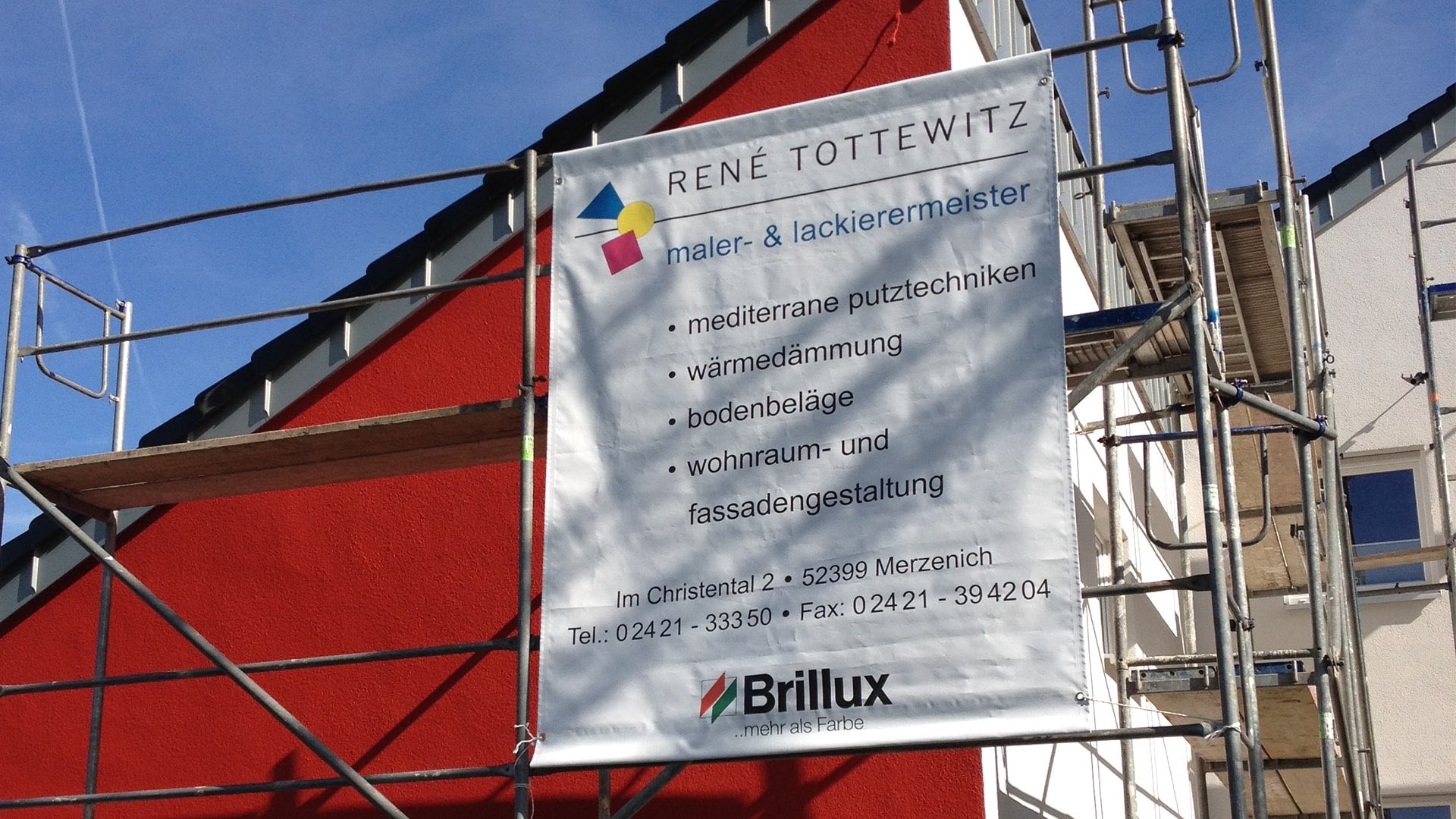 Rote Fassade mit Gerüst auf einer Baustelle des Malerbetriebs